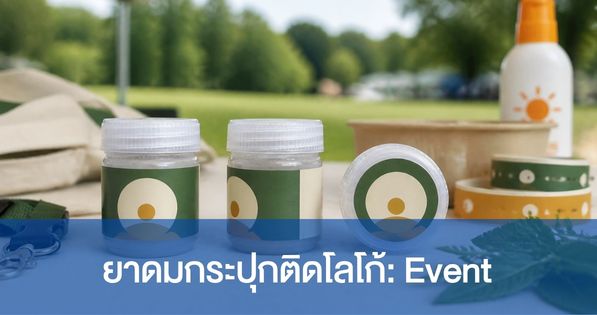 ยาดมสมุนไพรขนาด 5 กรัมติดฉลากองค์กร แสดงสามมุม ได้แก่ ด้านหน้า มุมสามส่วนที่เห็นรอยต่อฉลาก และด้านบนที่เห็นพื้นที่สติกเกอร์ฝา บนโต๊ะลงทะเบียนงานกลางแจ้ง